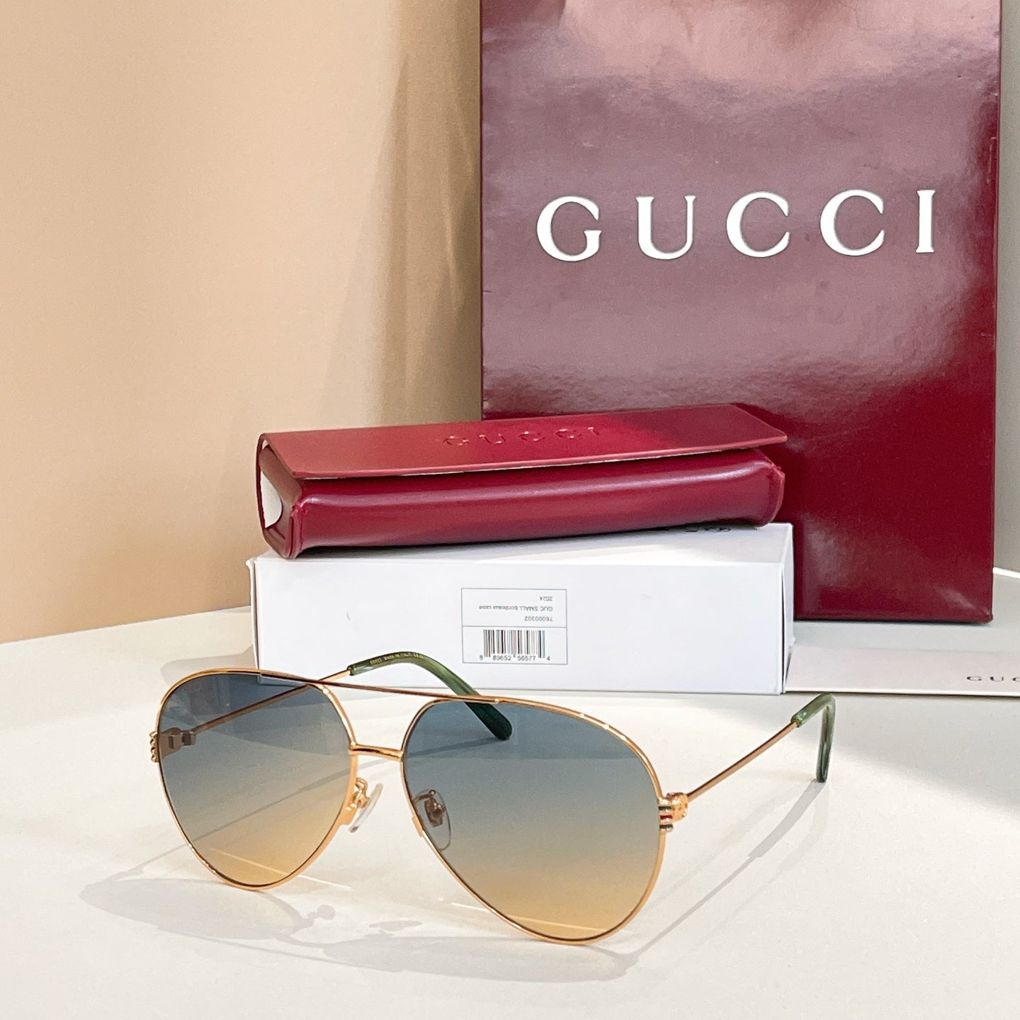 Gold-tone round sunglasses with light blue tinted lenses and green temple tips
