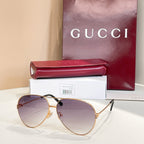 Gold-tone round sunglasses with tinted purple lenses and black logo detail on arms