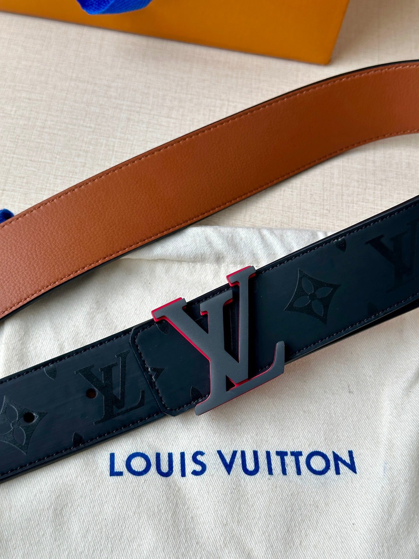 Louis Vuitton belt close-up: dark monogram strap with brown keeper and LV buckle