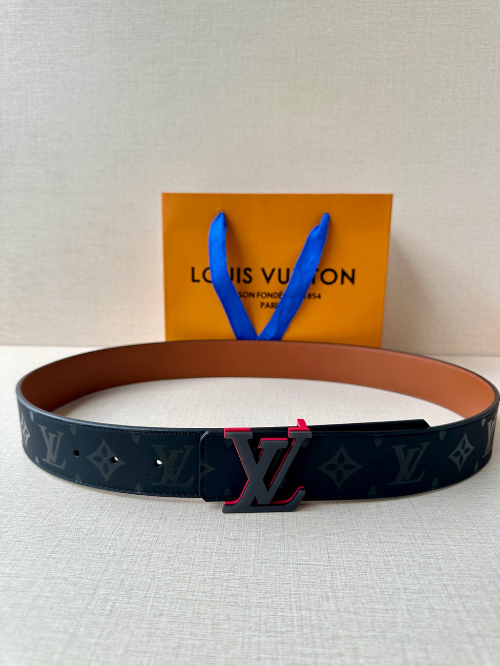 Louis Vuitton belt with dark monogram strap and red-accent LV buckle
