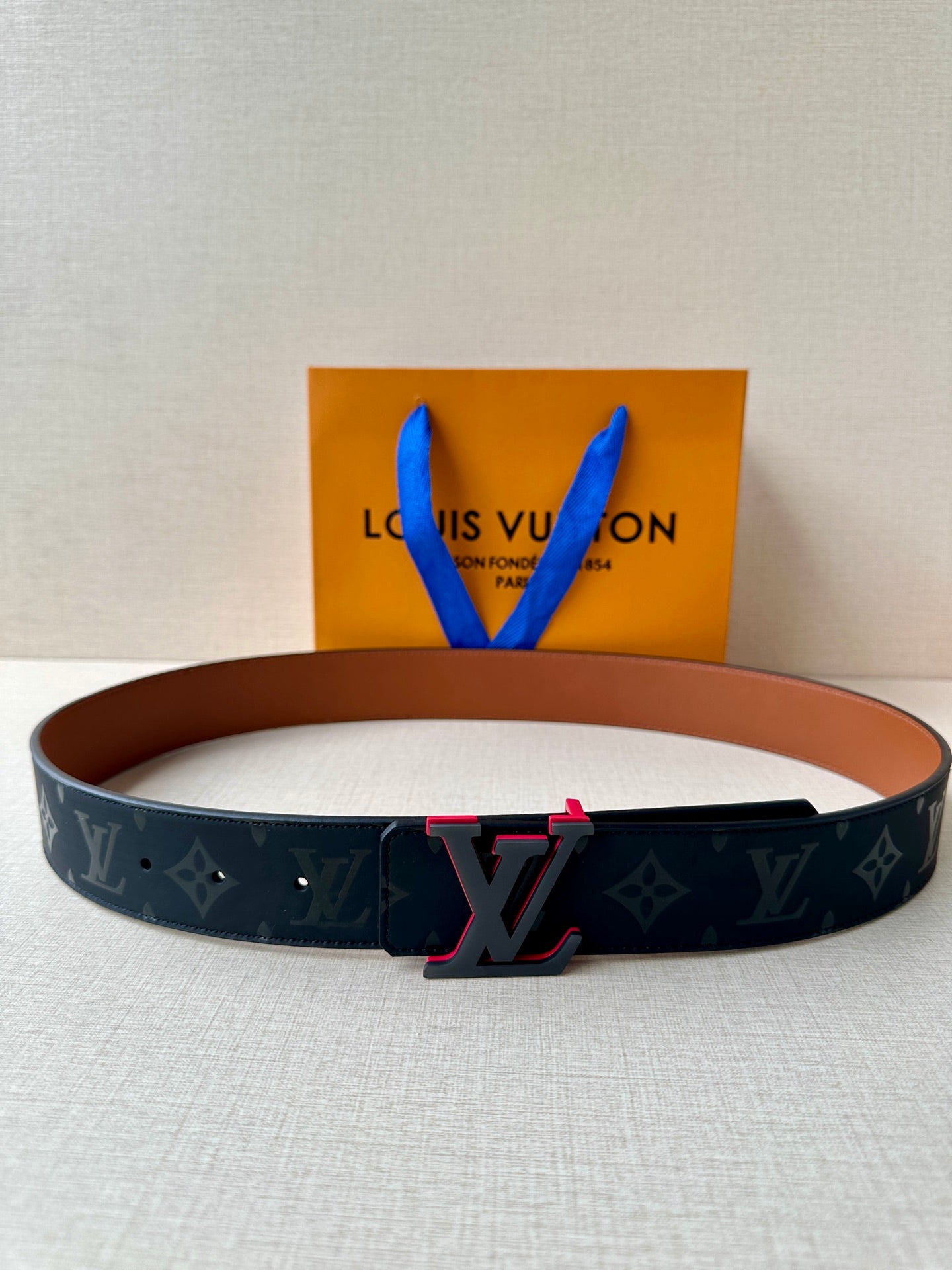 Louis Vuitton belt with dark monogram strap and red-accent LV buckle