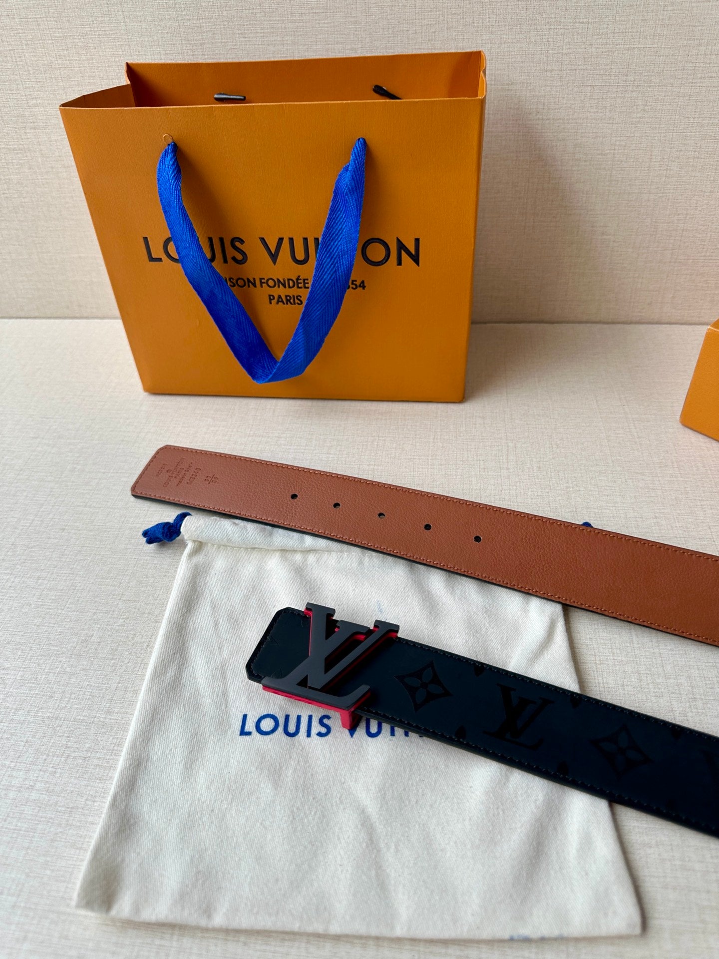 Louis Vuitton belt with brown leather strap, dark monogram face, and LV buckle