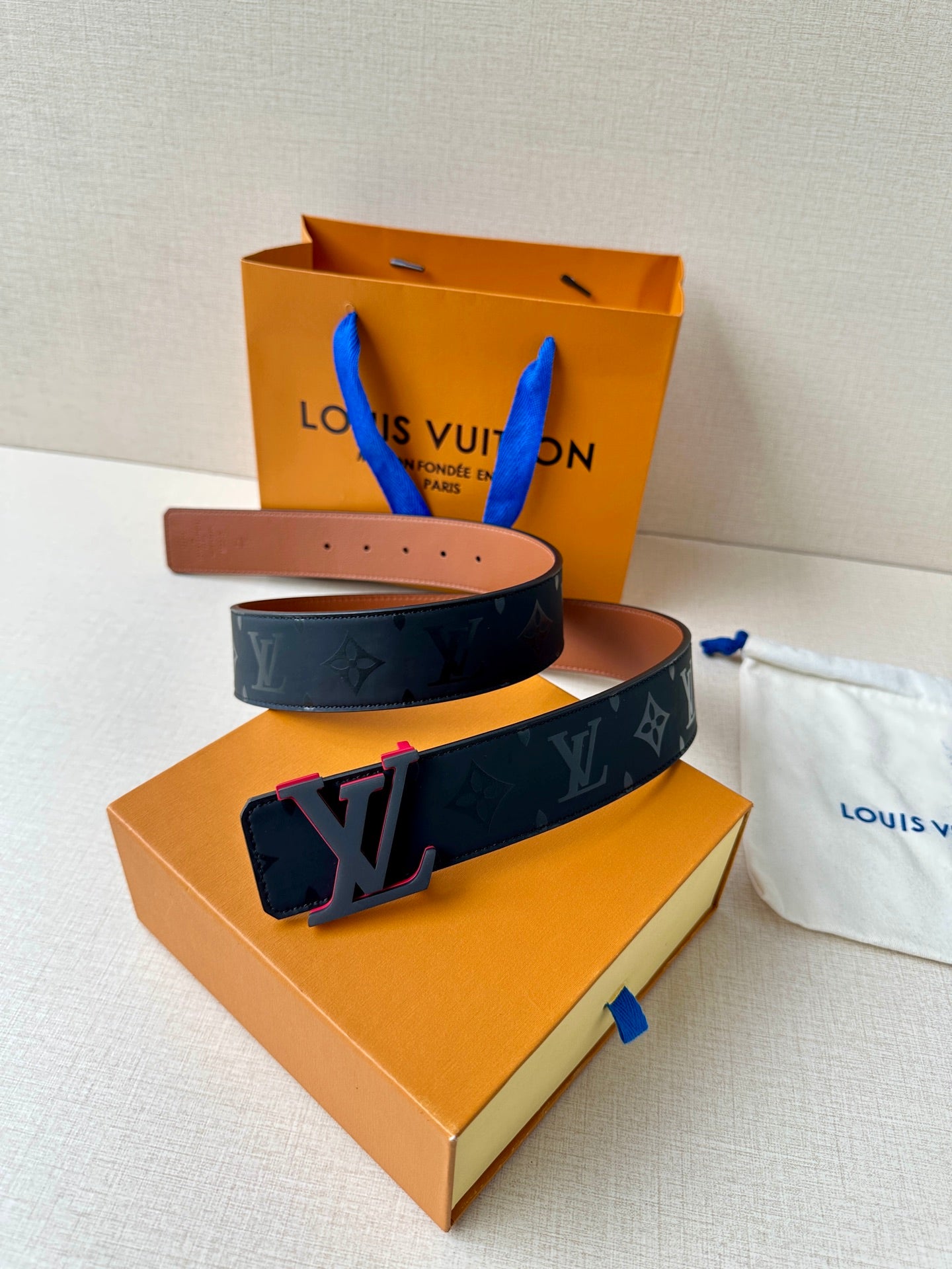 Louis Vuitton belt with dark monogram strap, brown keeper, and prong holes