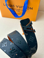Louis Vuitton belt: dark blue monogram strap, orange-toned buckle, adjustment holes.
