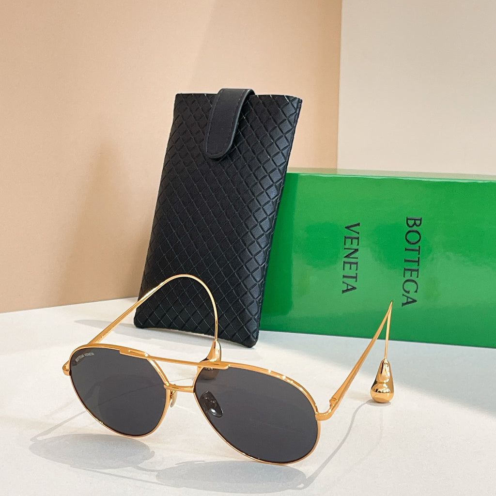 Bottega Veneta glasses with gold frame and dark lenses, beside black case