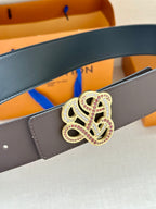 Dark navy leather belt with ornate gold-tone monogram buckle and visible pin holes