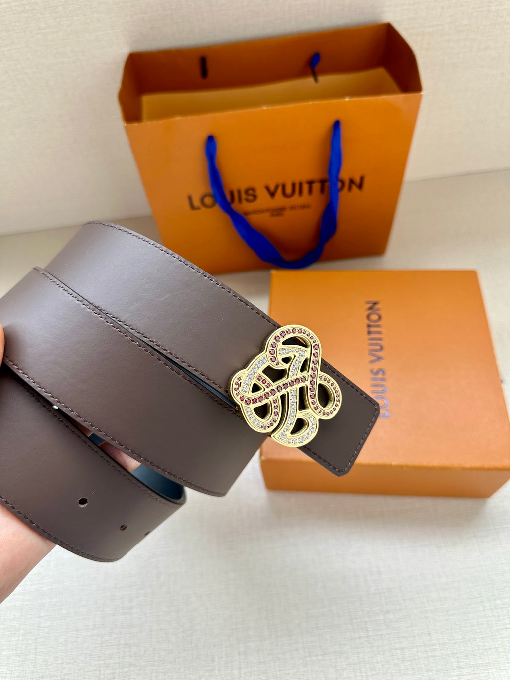 Dark navy leather belt with large gold-tone monogram buckle, laid flat