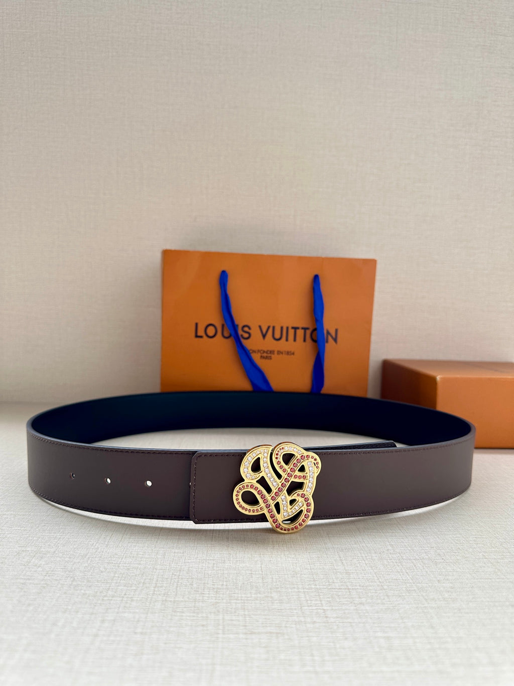 Dark navy leather belt with gold-tone embellished monogram buckle and stitched edge