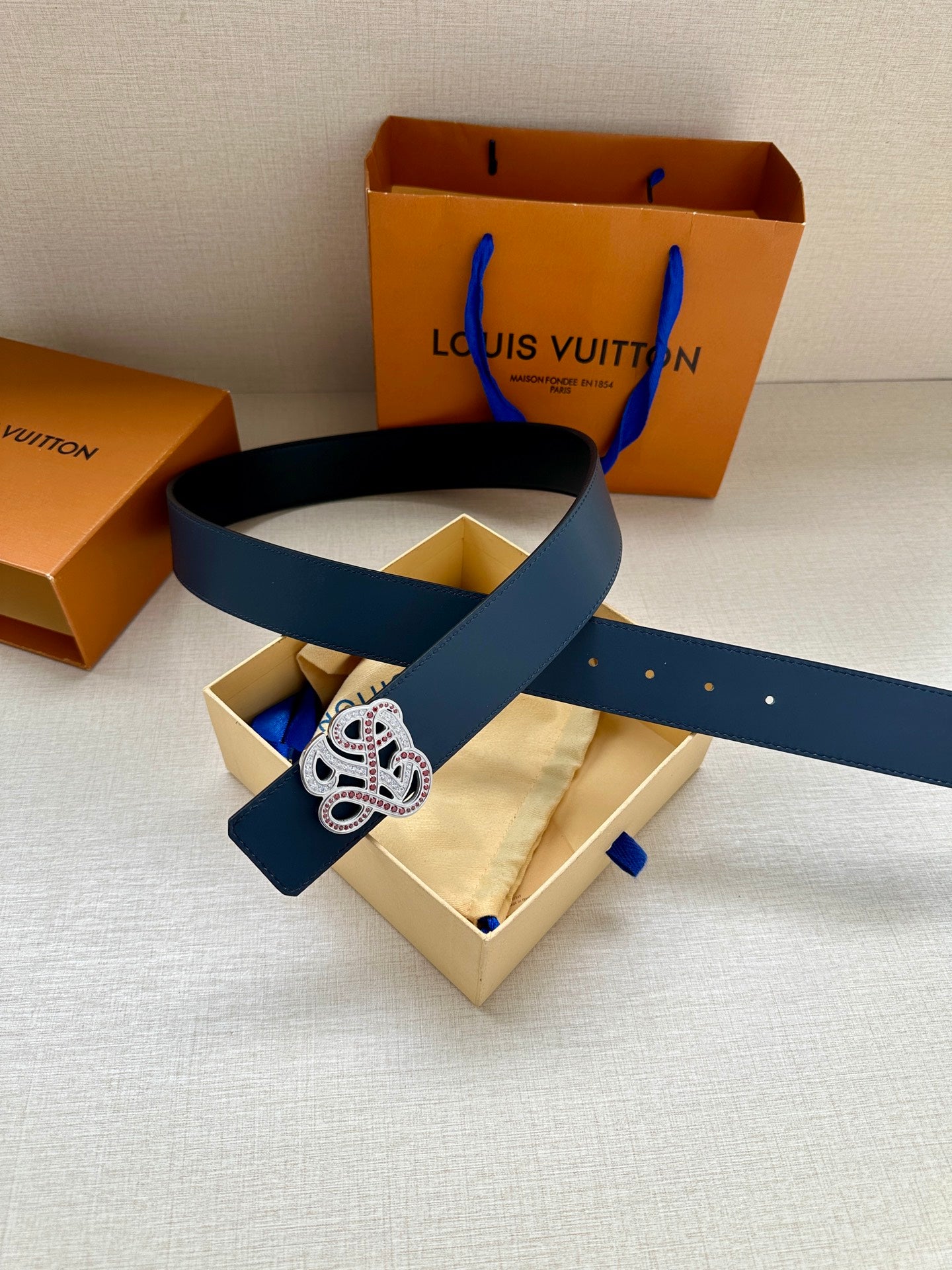 Dark blue leather belt with logo buckle laid on gift boxes