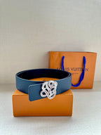 Dark blue leather belt with ornate buckle on top of orange gift box