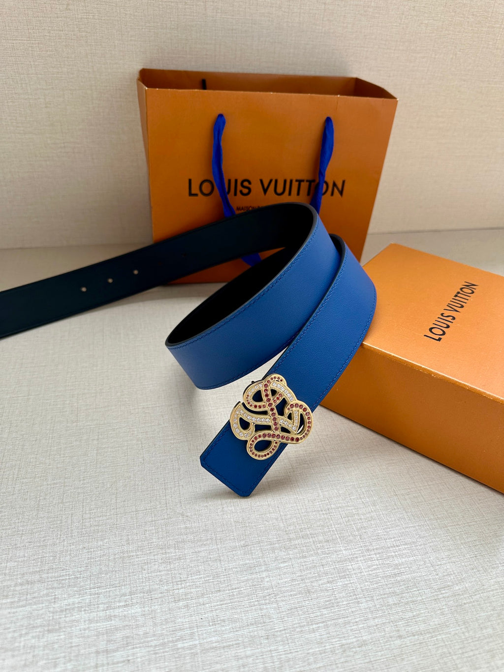 Blue leather belt with gold-toned ornate buckle on strap end