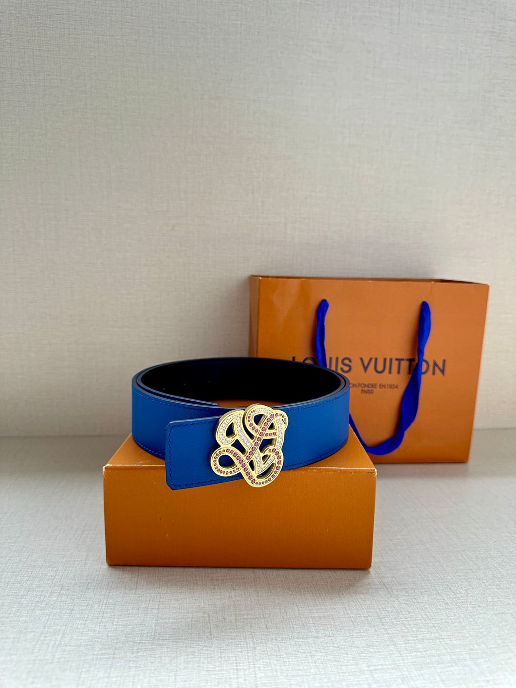 Blue leather belt with ornate gold-toned buckle on center strap