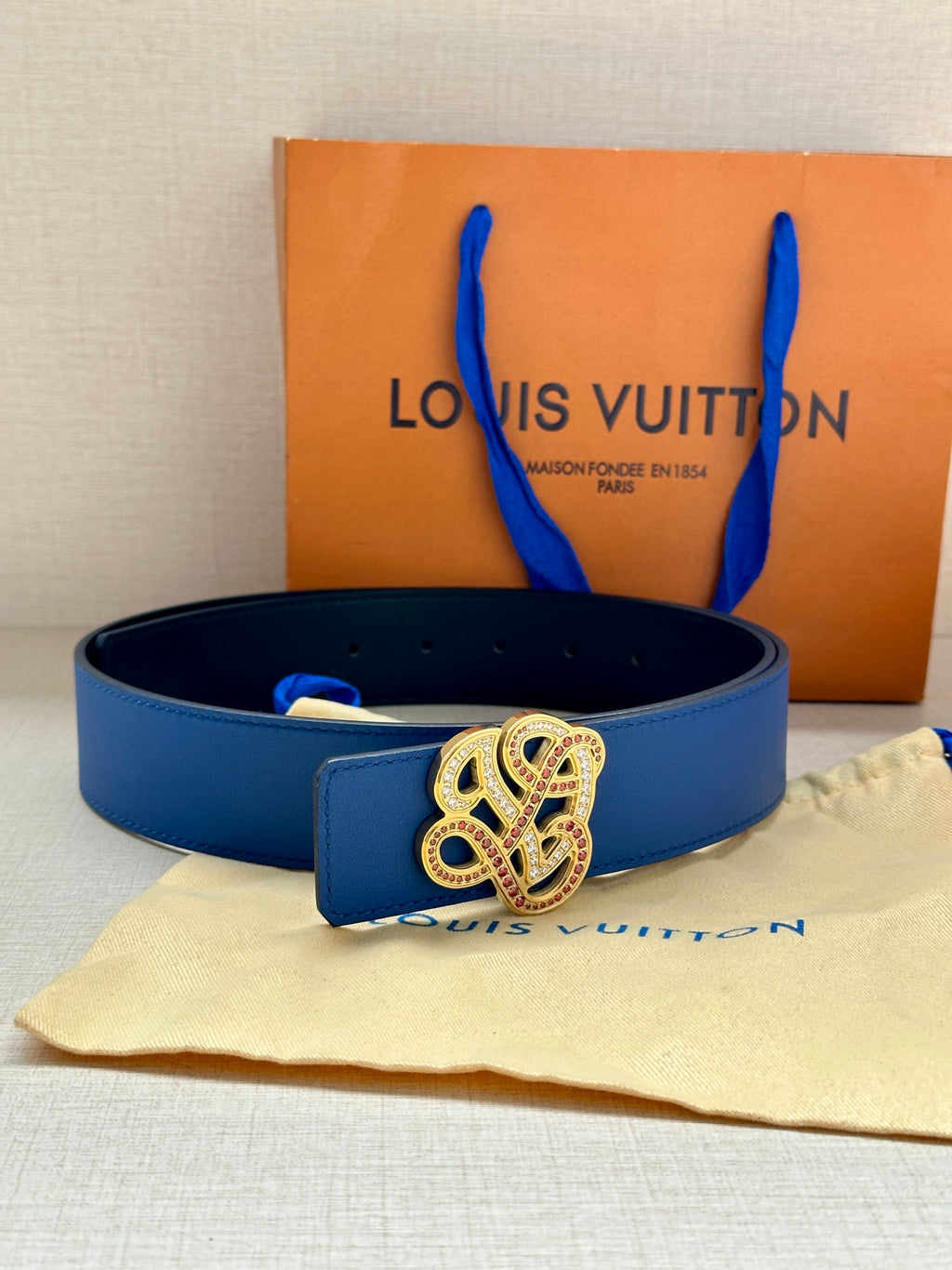Blue leather belt with ornate gold and silver buckle and strap keeper