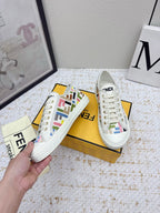Fendi low-top sneakers, white canvas with colorful logo accents, held by hand
