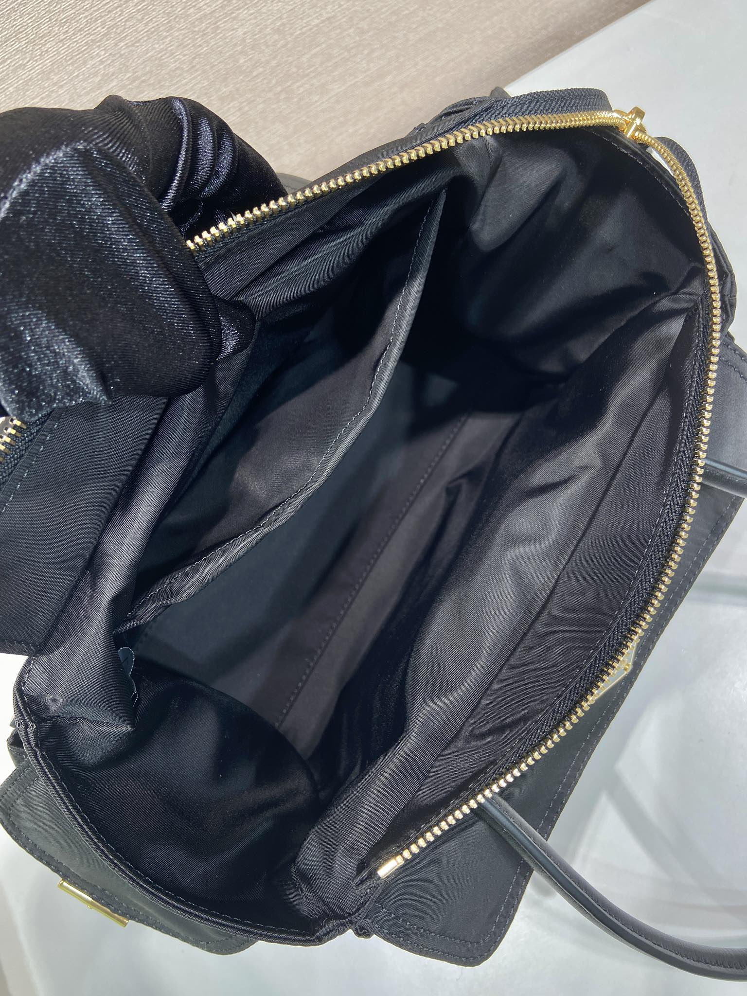 Prada black bag open top with dark interior lining and gold zipper trim
