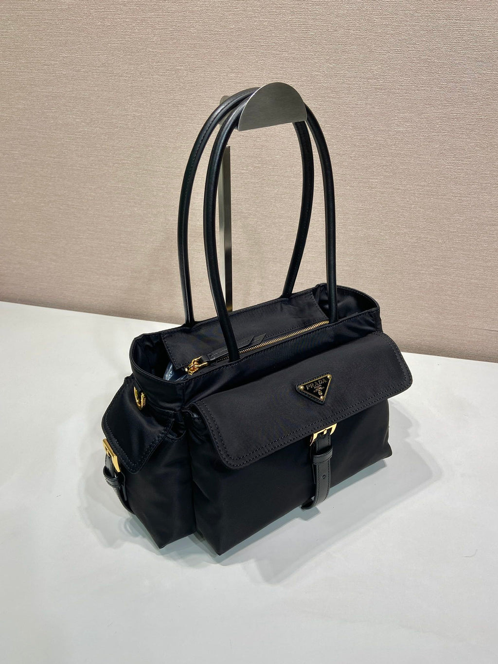 Prada black tote bag with side flap pocket, shoulder strap, and logo badge