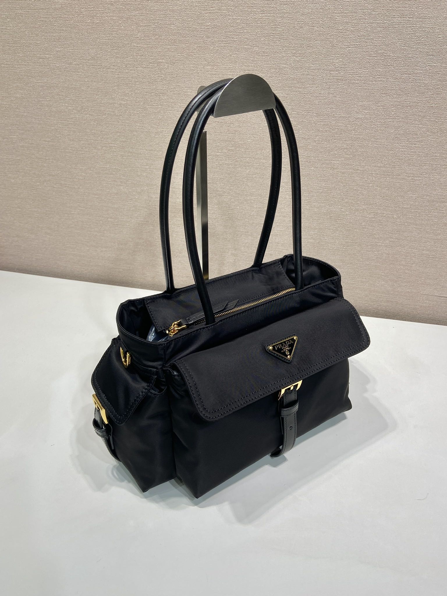 Prada black tote bag with side flap pocket, shoulder strap, and logo badge