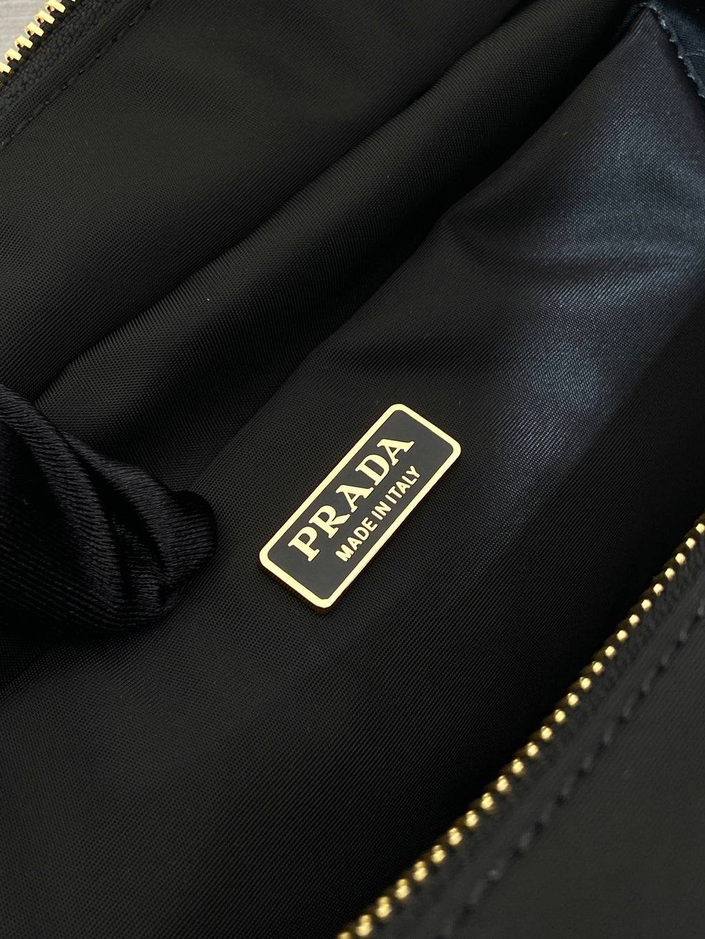Prada label on black bag interior lining with gold text hardware