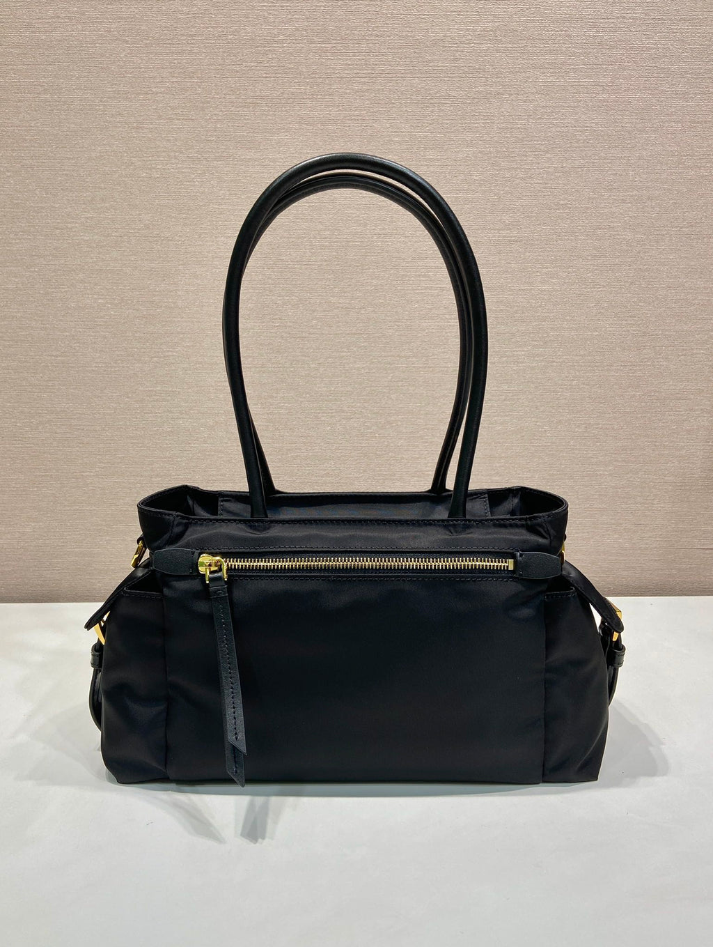 Prada black tote bag front view with top handles and gold zipper pocket