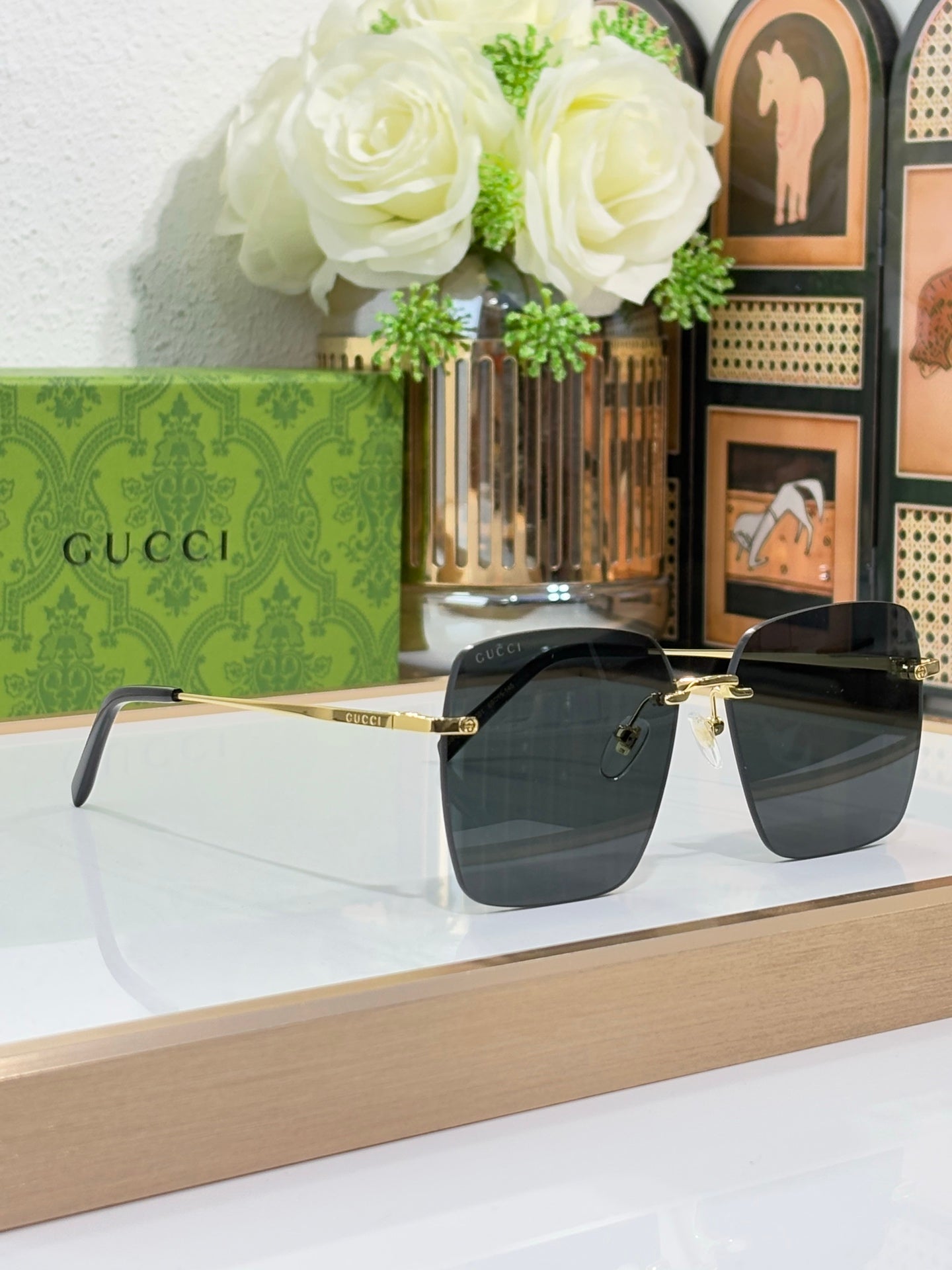 Gucci sunglasses with gold-tone frame and dark lenses, on stand display angle.