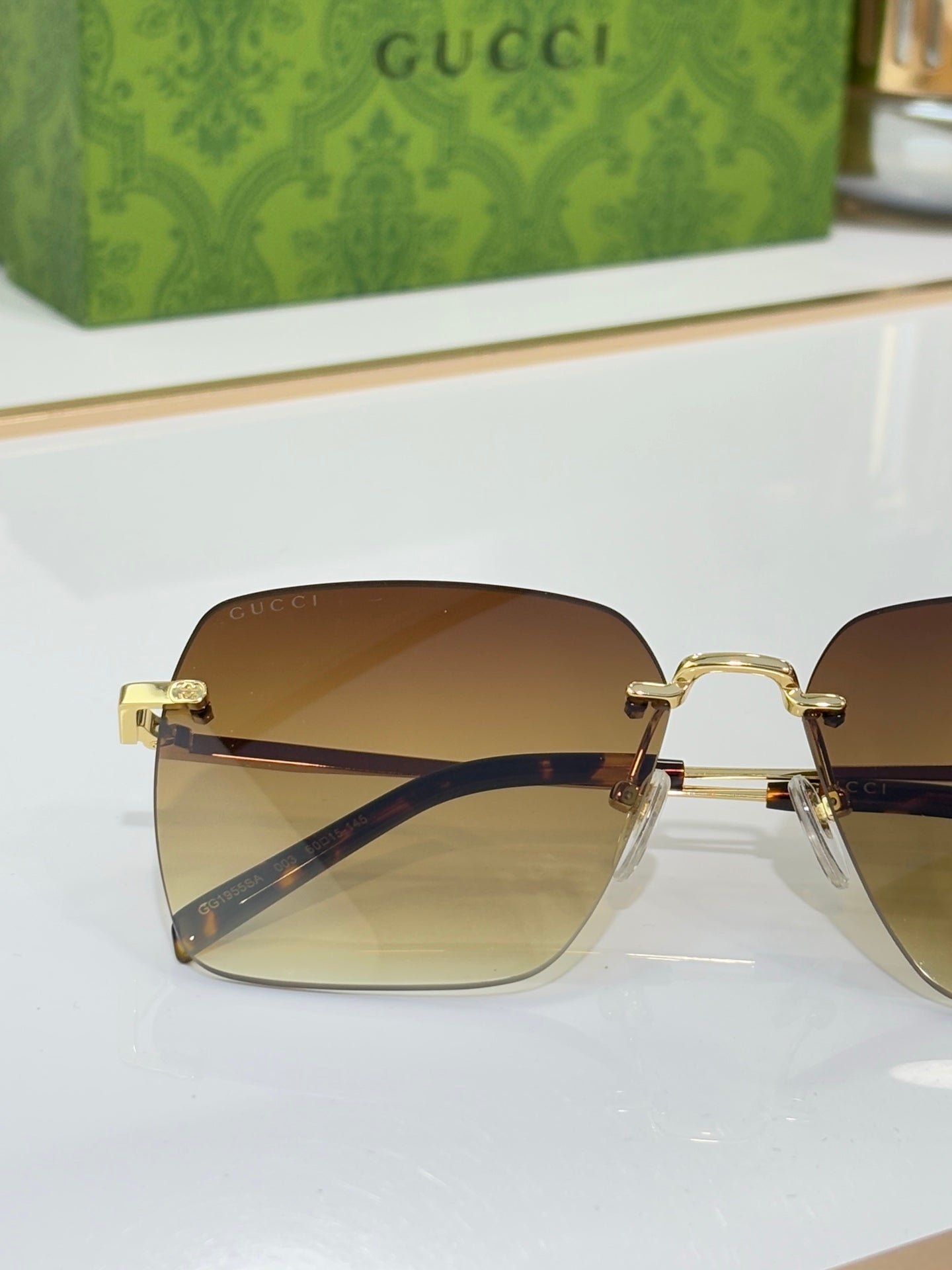 Gucci sunglasses with gold hinges and amber-gradient lenses, close side view.