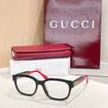 Gucci eyeglasses with black frames, green temples, and red accents; clear lenses.