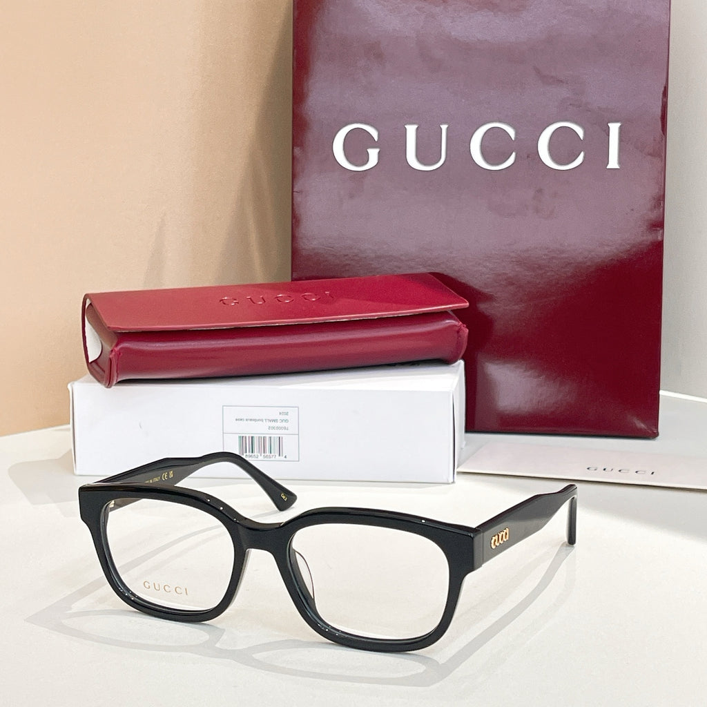 Gucci eyeglasses with black frames and red temple accents; clear lenses.