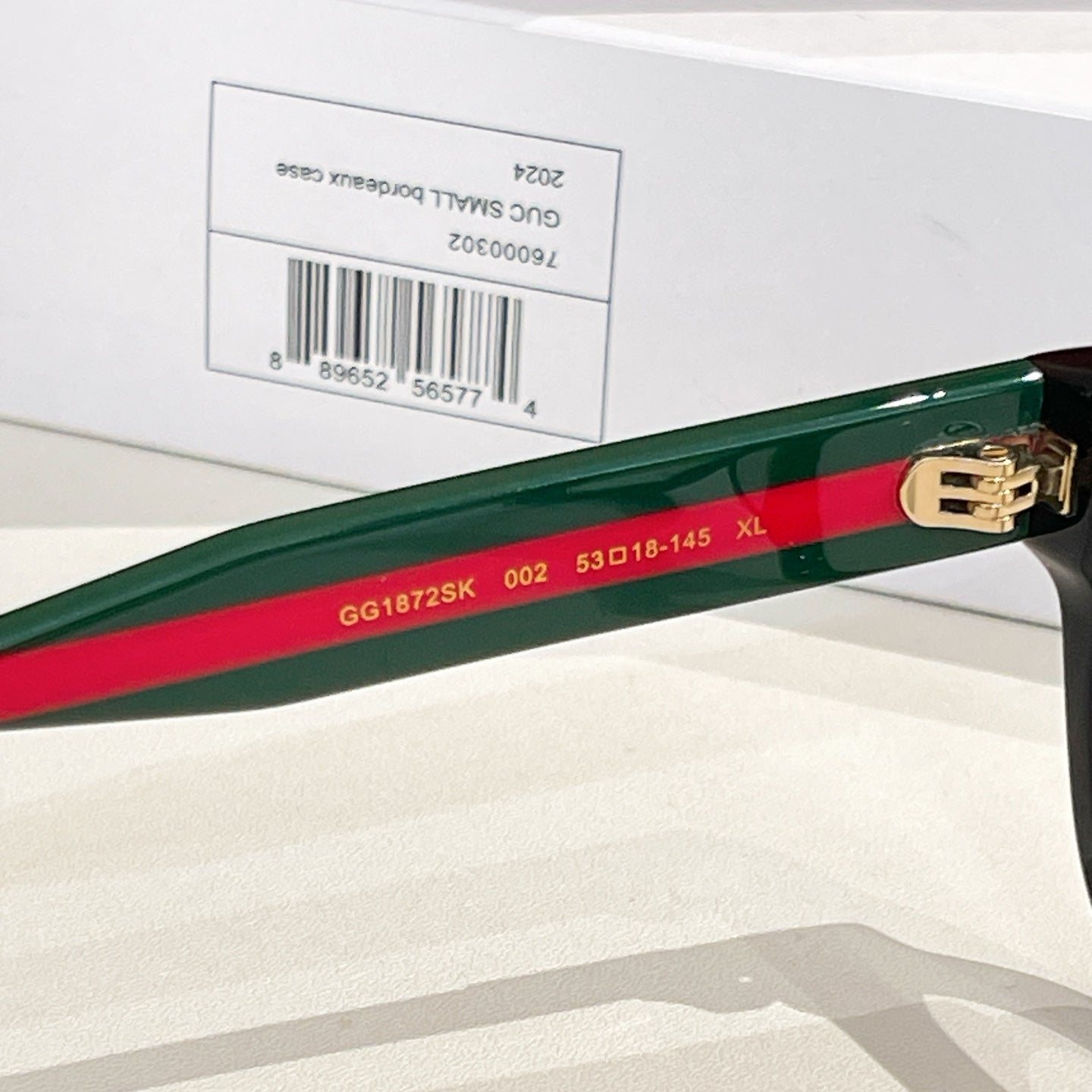 Gucci eyeglasses close-up: green temple with red stripe and gold logo detail.