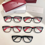 Multiple Gucci eyeglasses with dark frames and red-and-green temple details; clear lenses.