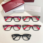 Six Gucci eyeglasses on display with black frames and red-and-green temple details.