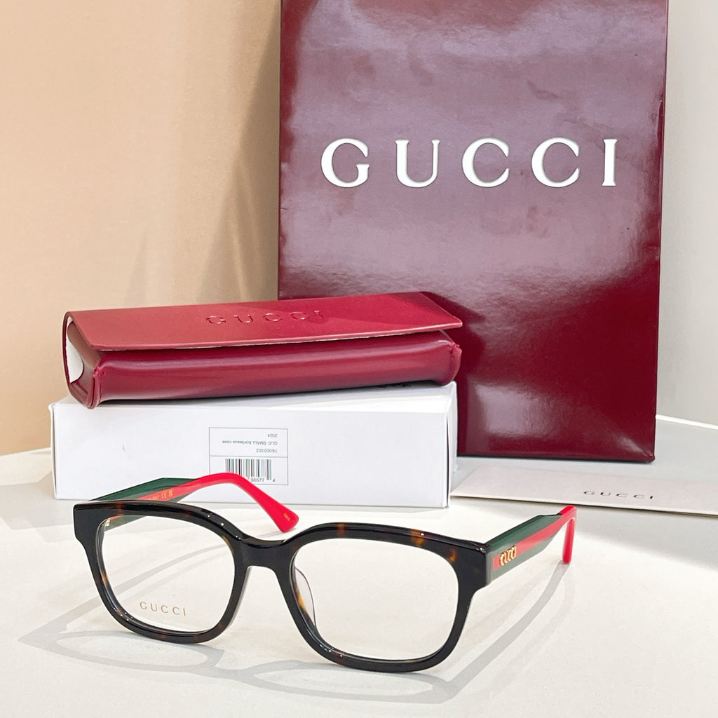 Gucci eyeglasses with black frames, red temples, and green accents; clear lenses.