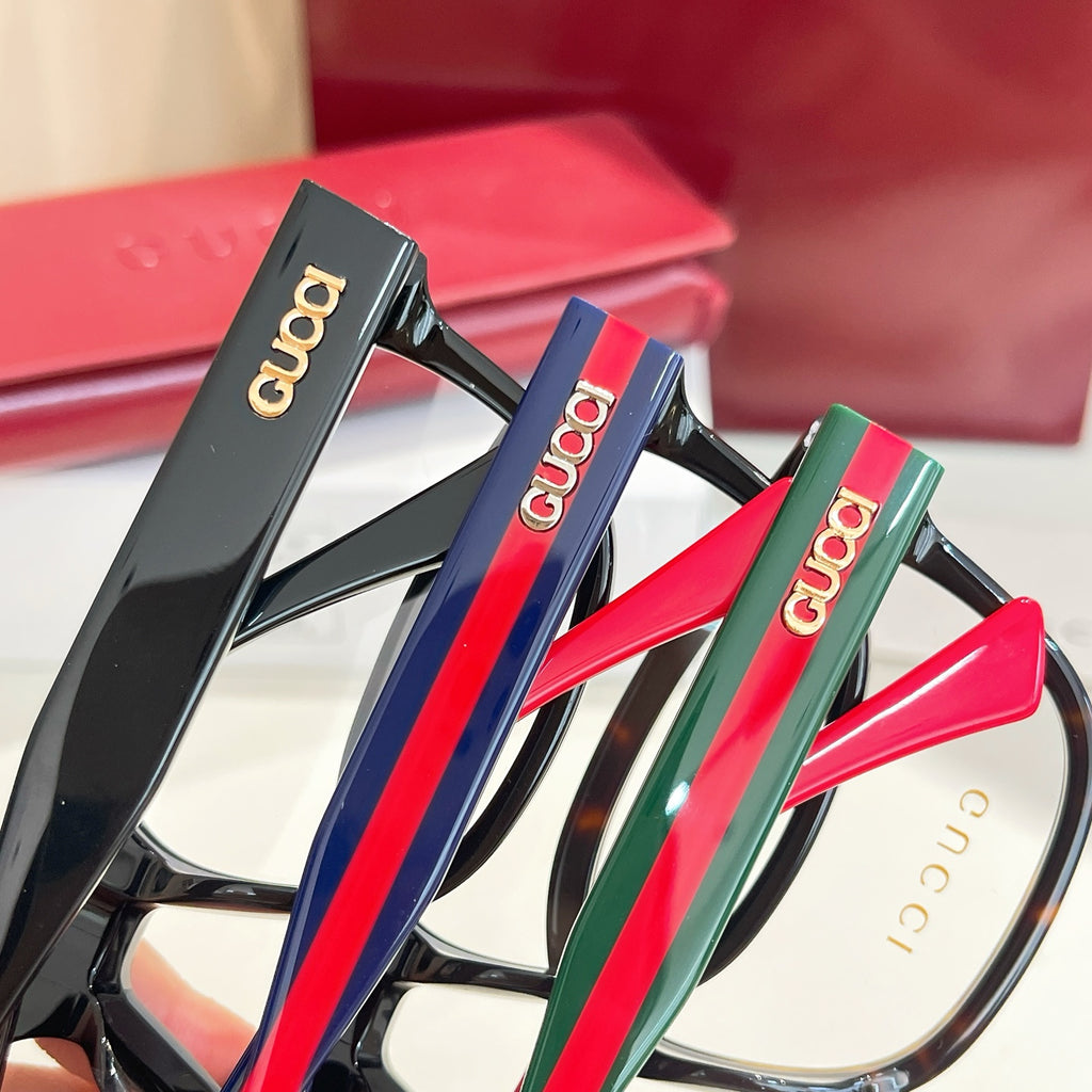 Set of Gucci eyeglasses with dark frames and colorful temples: red, blue, and green.