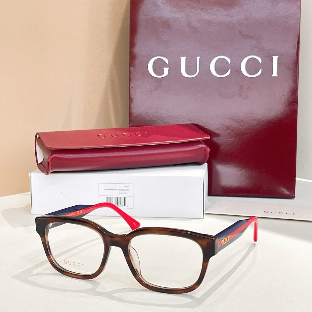 Gucci eyeglasses with tortoise frames, green temples, and red accents; clear lenses.