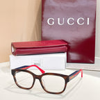 Gucci eyeglasses with tortoise frames, green temples, and red accents; clear lenses.