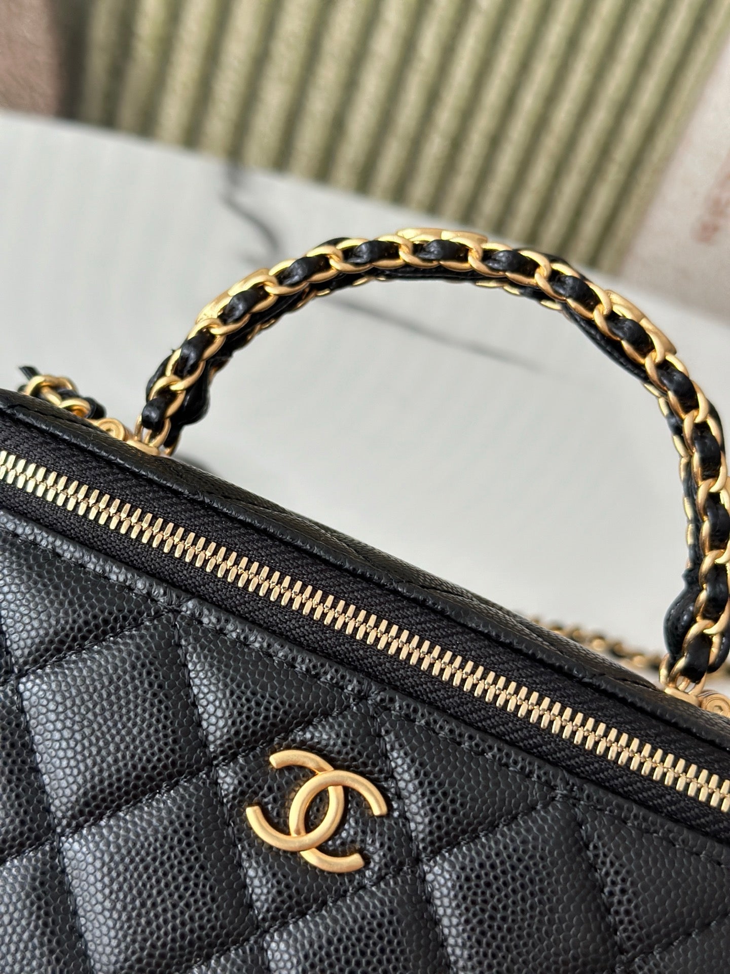 Chanel mini bag close-up of gold zipper and Chanel logo on quilted black leather