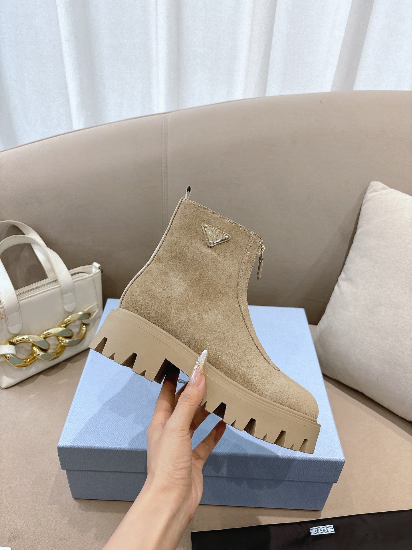 Beige suede Chelsea ankle boots with triangular logo patch and ridged lug sole