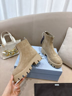 Beige suede ankle boots with lug soles, side elastic gore, and heel pull tab