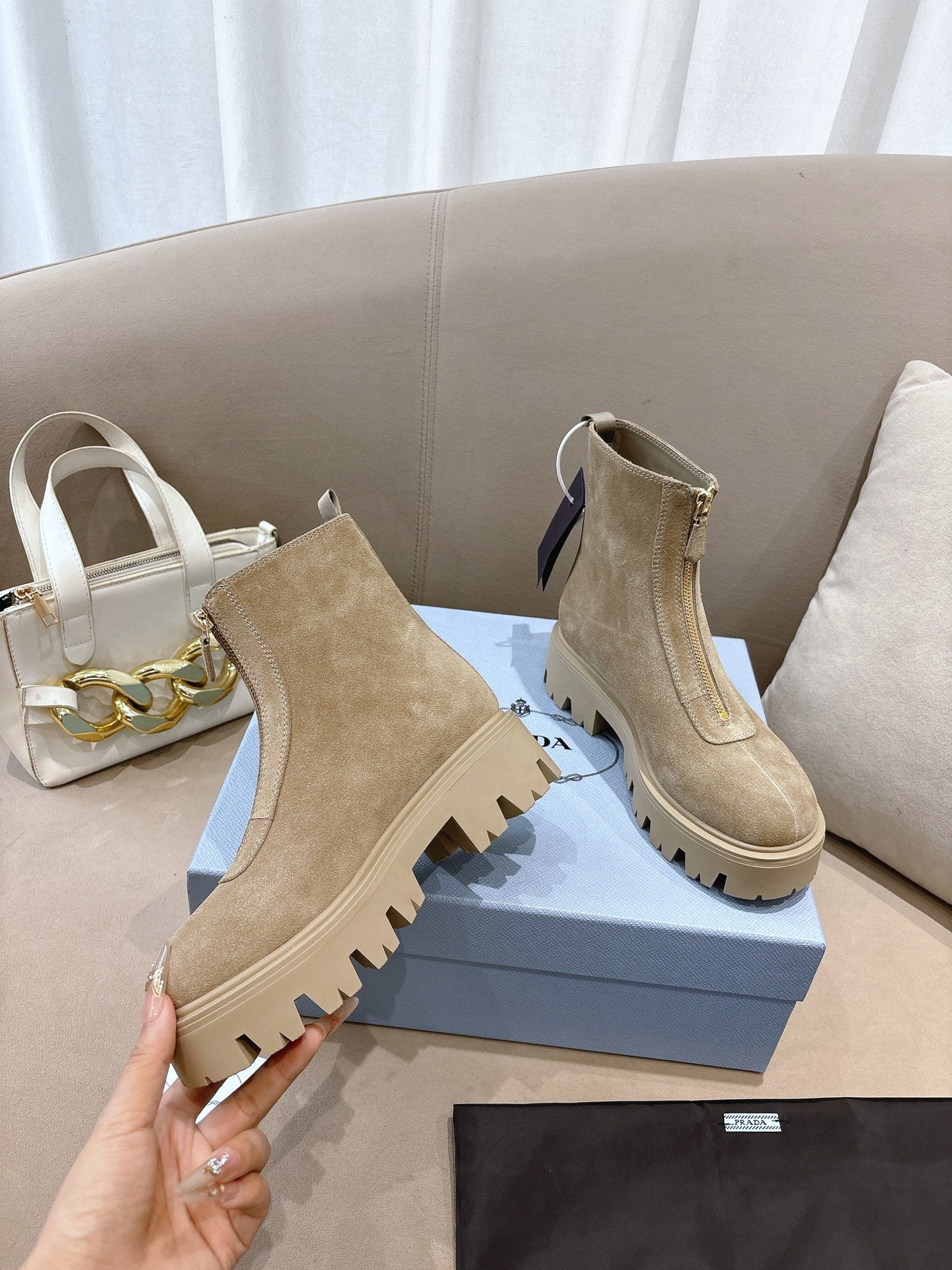 Beige suede ankle boots with lug soles, side elastic gore, and heel pull tab