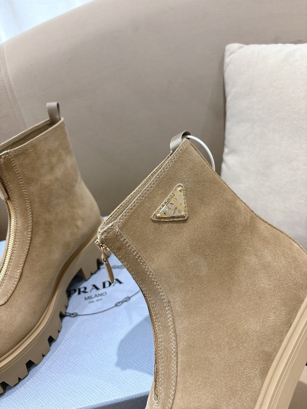 Beige suede Chelsea boot with triangular logo patch, side elastic gore, and pull tab