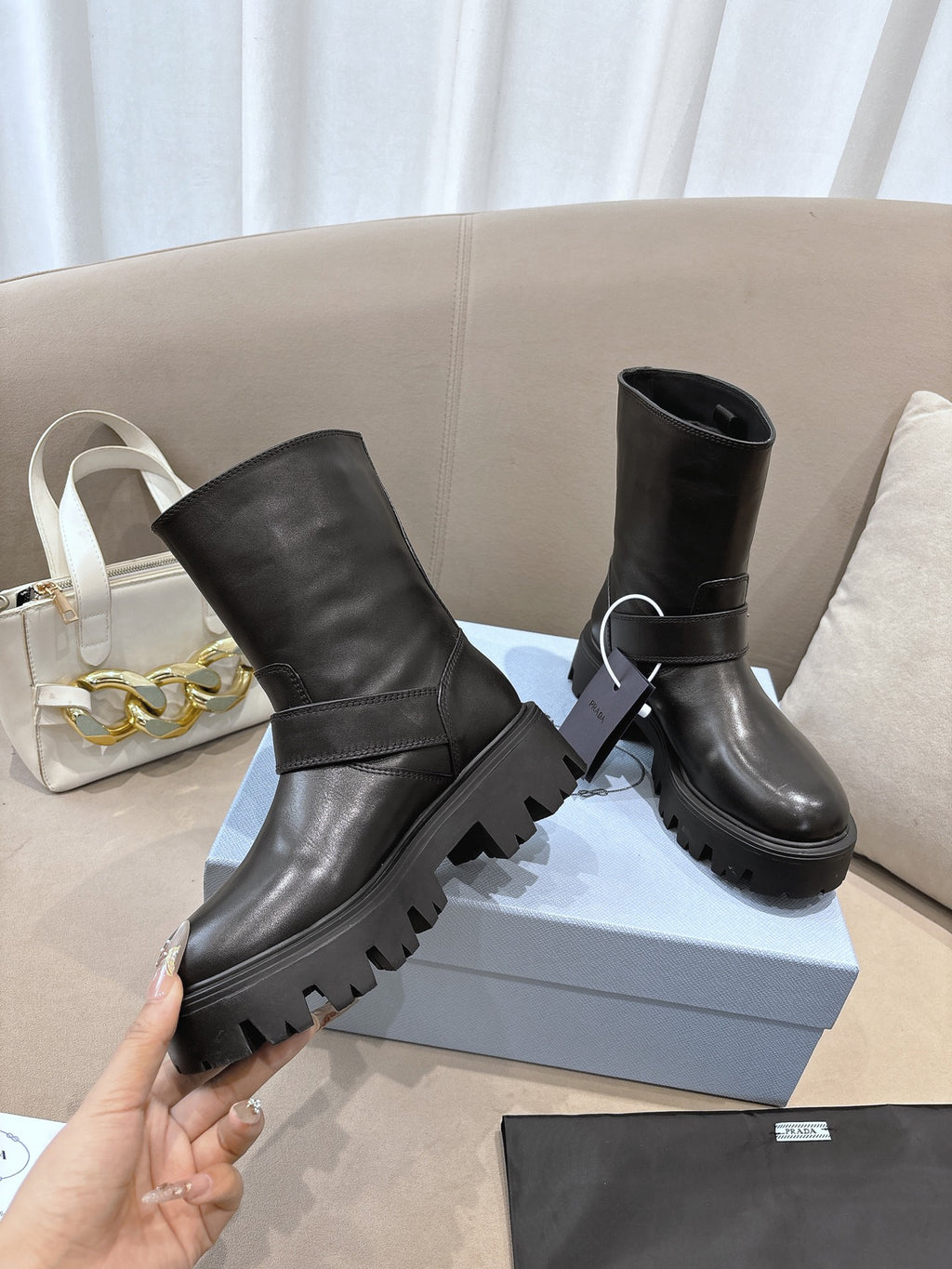 Prada ladies black leather mid-calf boots, one hand holding, buckle strap, lug sole