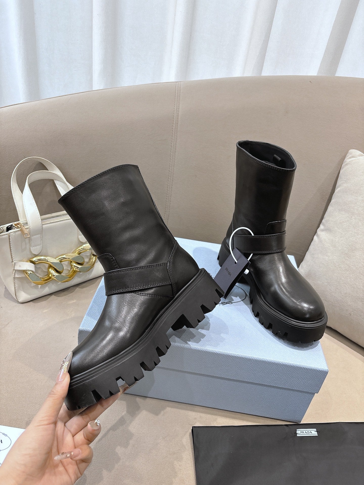 Prada ladies black leather mid-calf boots, one hand holding, buckle strap, lug sole