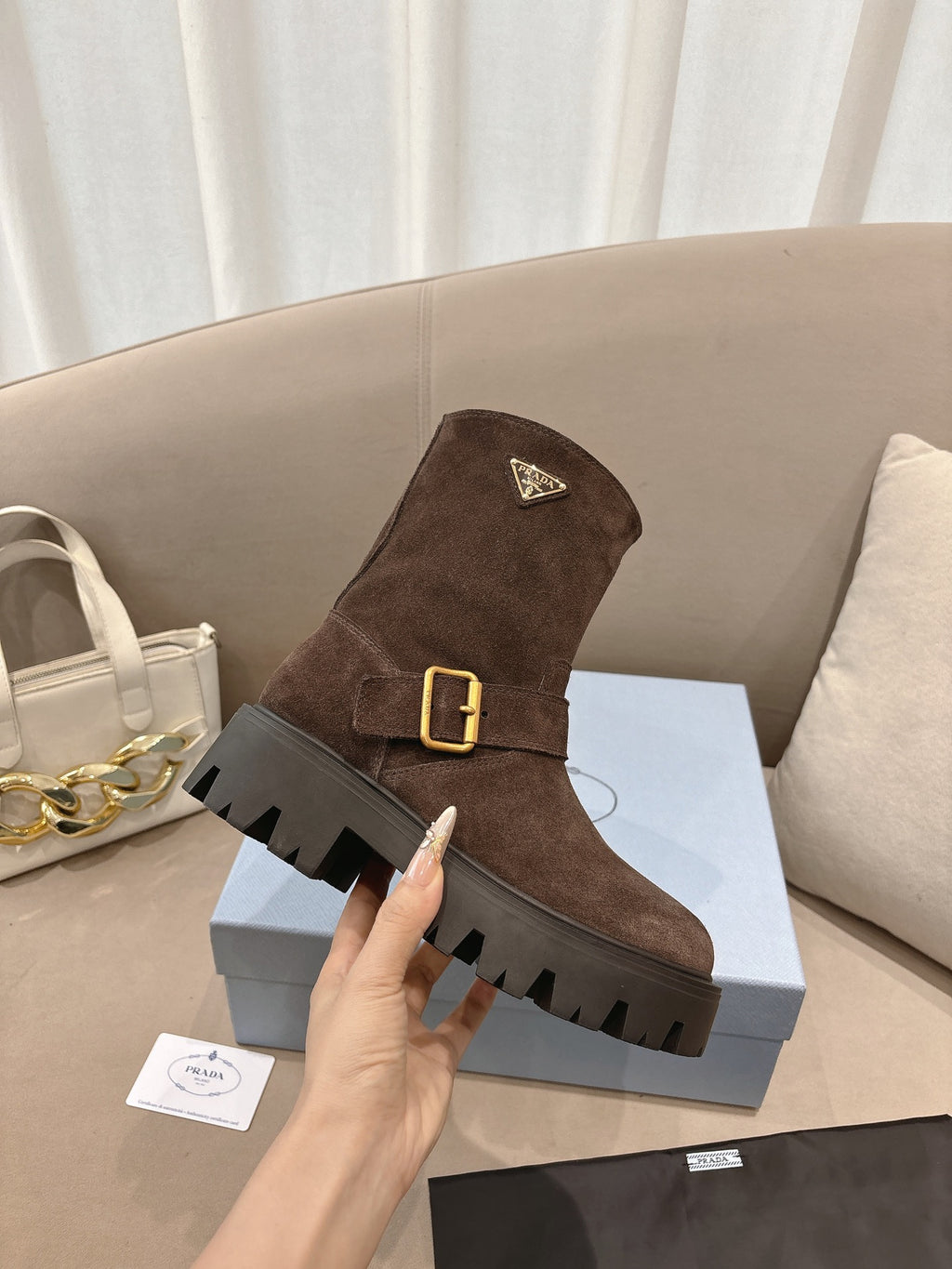 Brown suede ankle boots with gold buckle and triangular logo detail