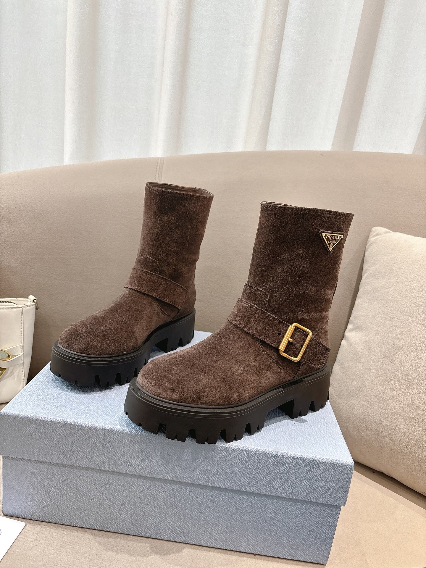Brown suede ankle boots with gold buckle and triangular logo patch