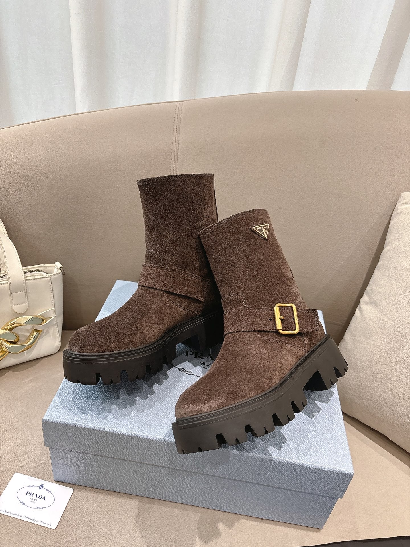 Brown suede ankle boots with gold buckle, side strap, and rugged lug sole