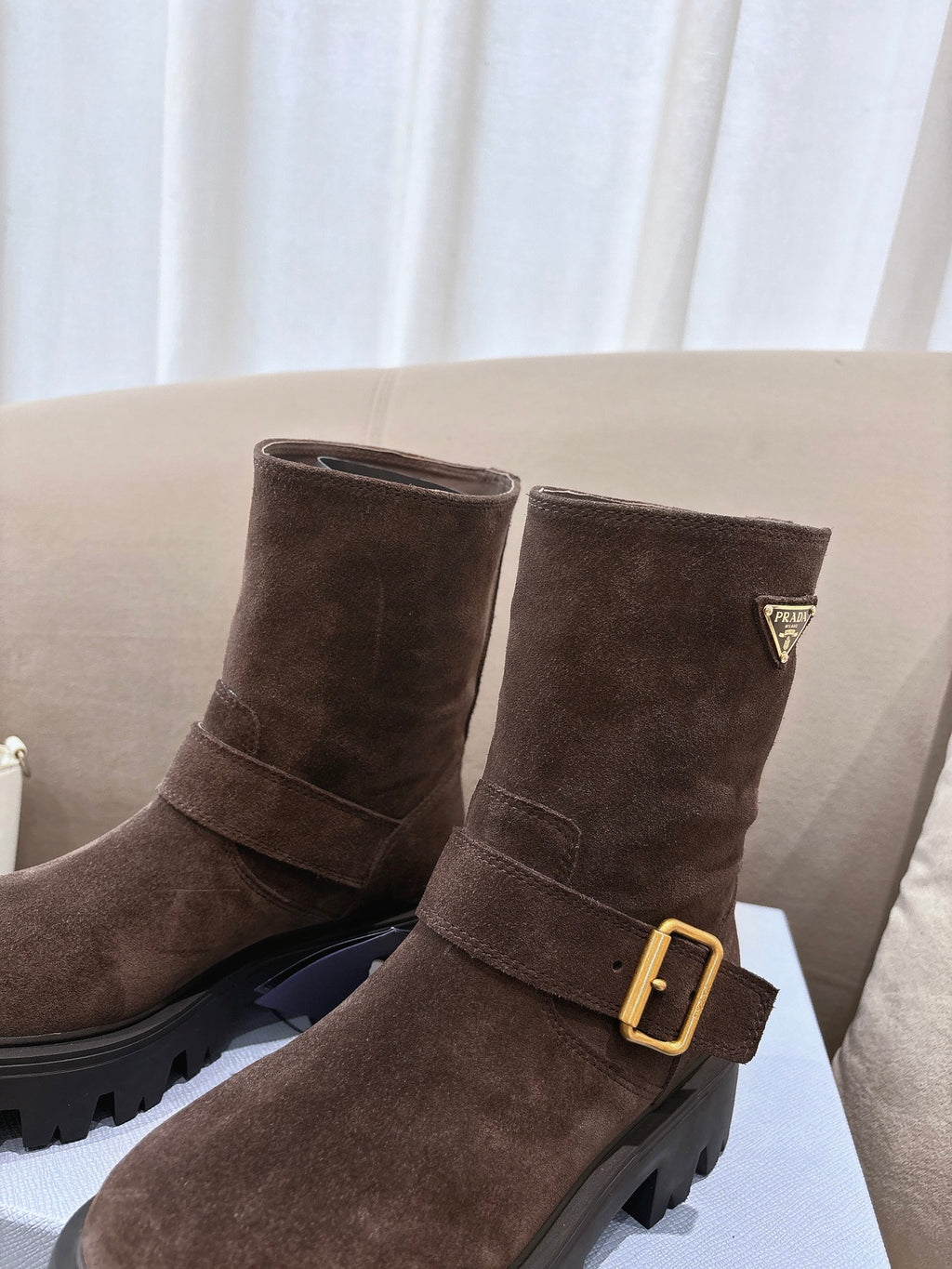 Brown suede ankle boots with gold buckle and triangular logo patch detail