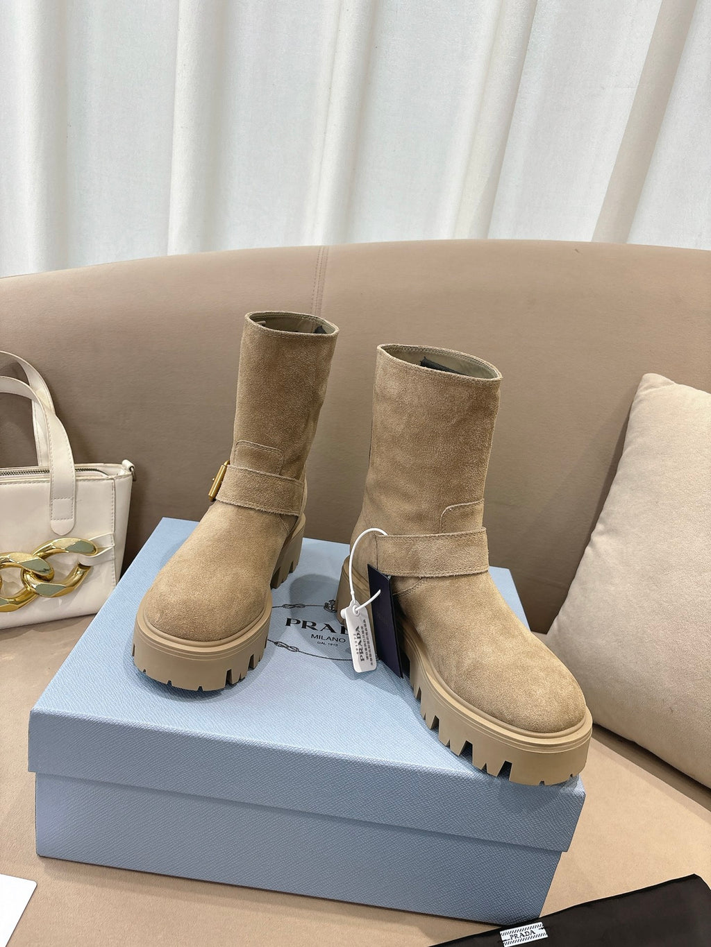 Prada women's suede ankle boots, beige, low shaft with buckle strap detail and lug soles.