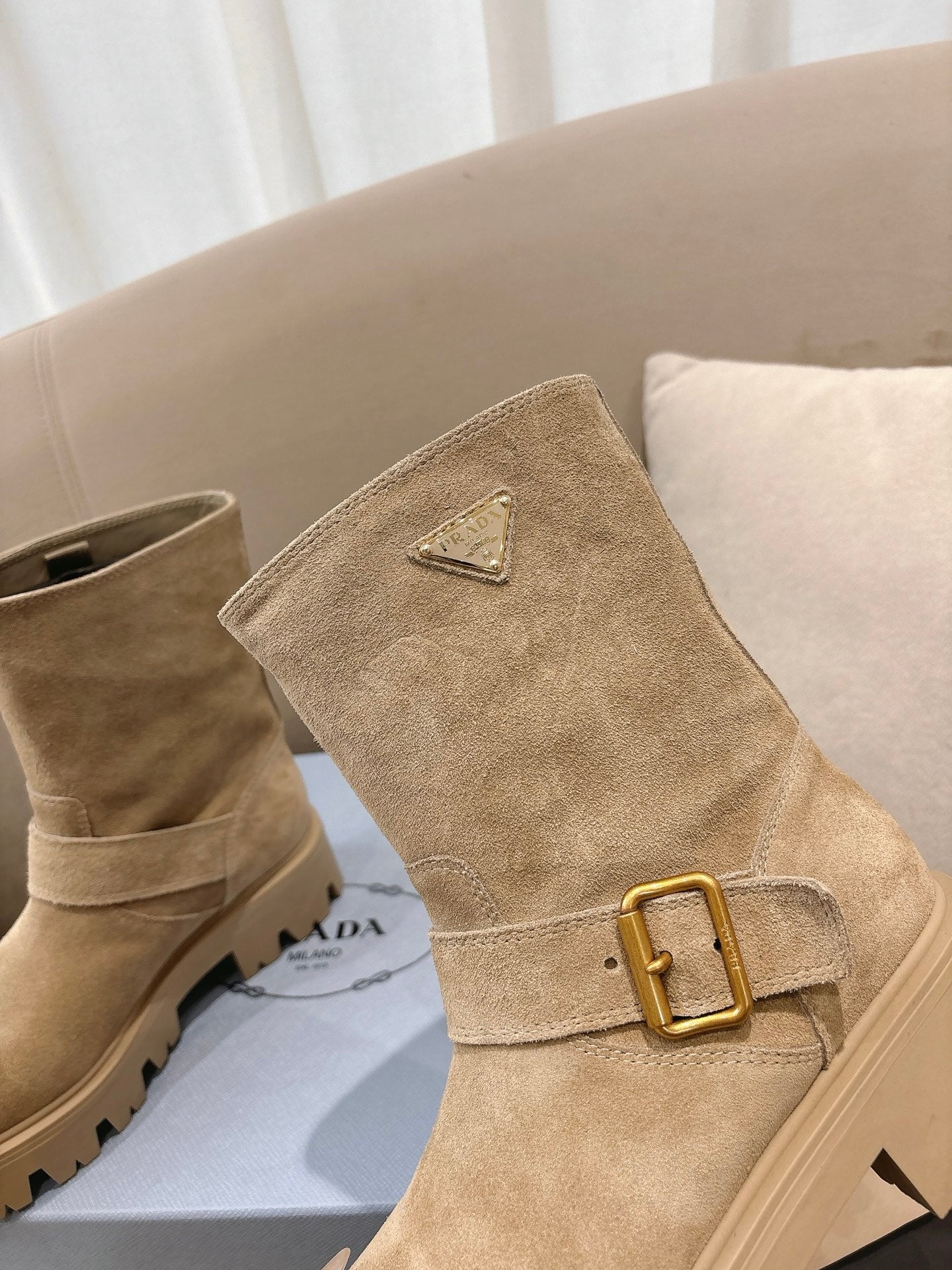 Prada women's suede ankle boots, beige, angled view showing gold-tone buckle and lug sole.
