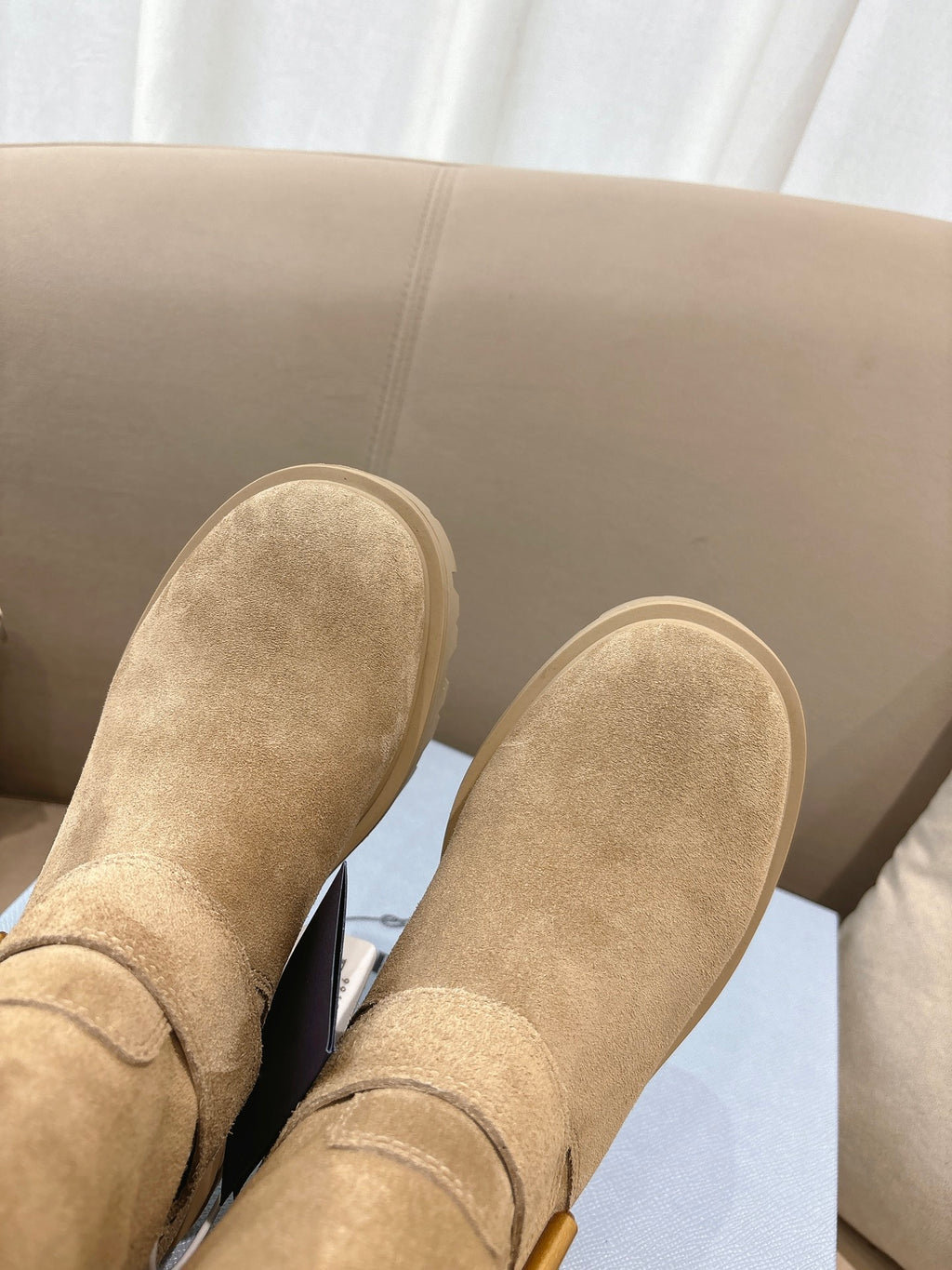 Prada women's suede ankle boots, beige, close-up of toe and stitched strap detail.