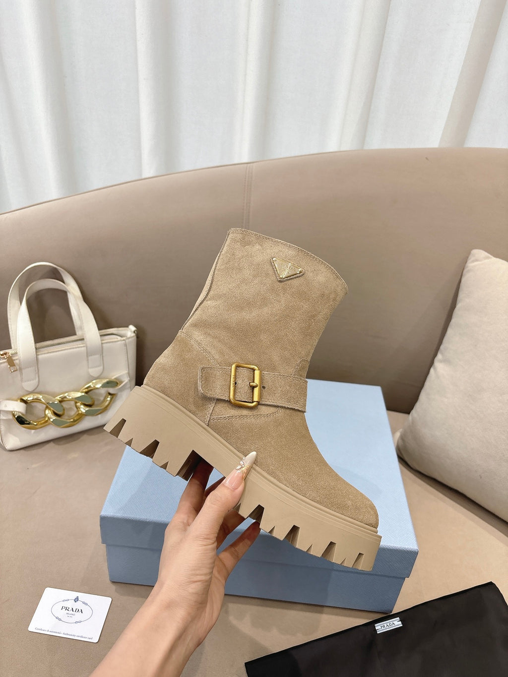 Prada women's suede ankle boots, beige, with square gold-tone buckle on side.