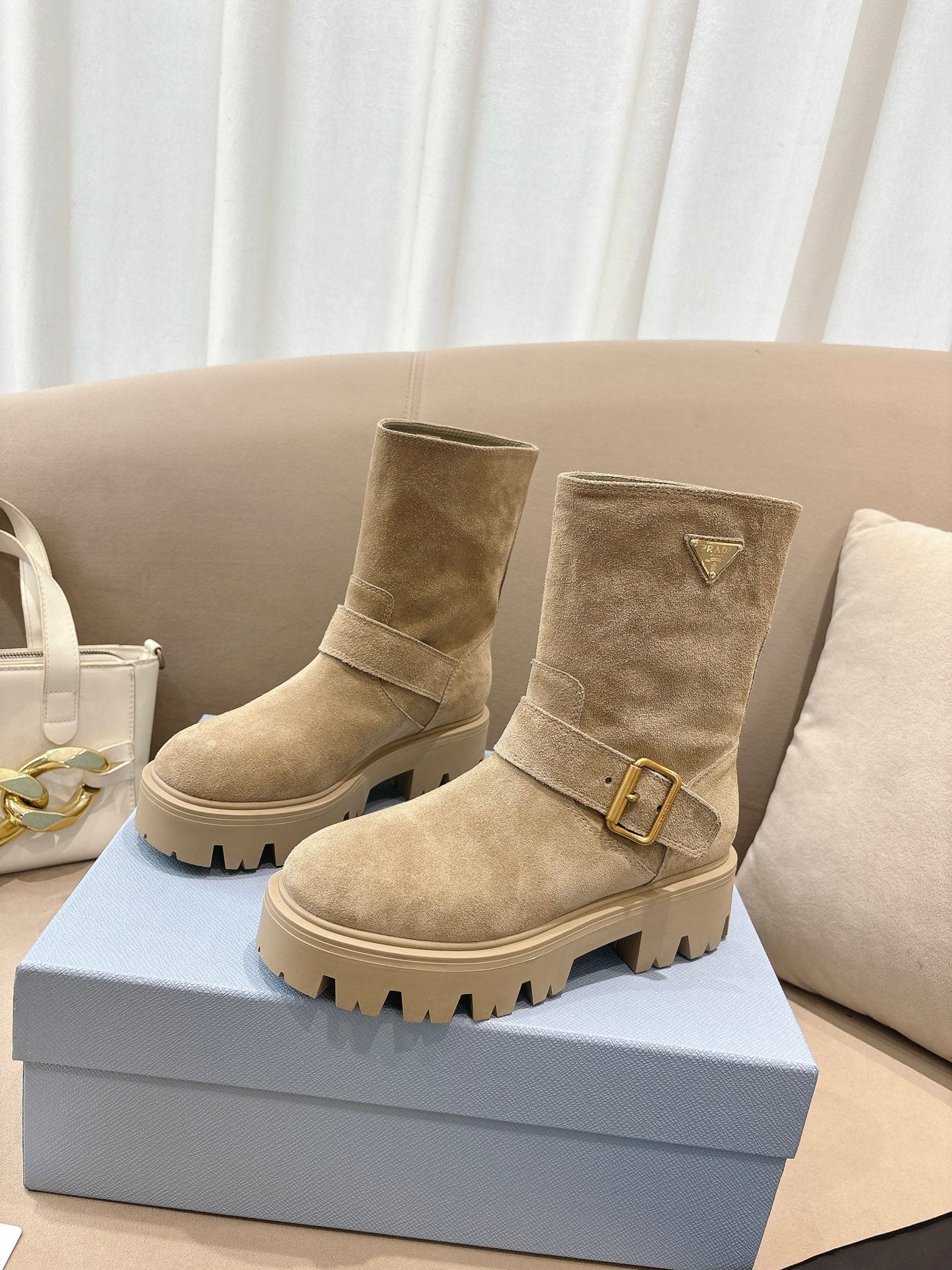 Prada women's suede ankle boots in beige, with buckle strap and thick lug platform sole.